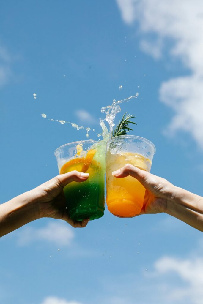 pexels-photo-8679650-8679650 Two colorful cocktails clinked against a bright blue sky, celebrating summer in style.